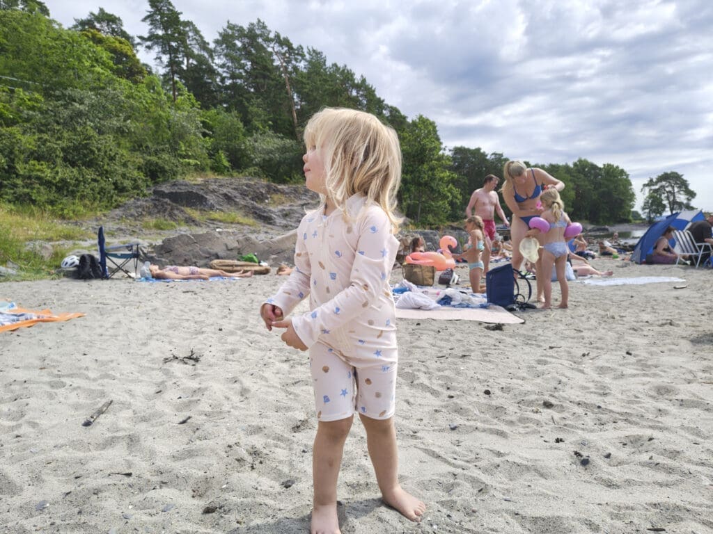 Jente i rosa badedrakt på sandstrand, fotografert med Motorola Edge 70